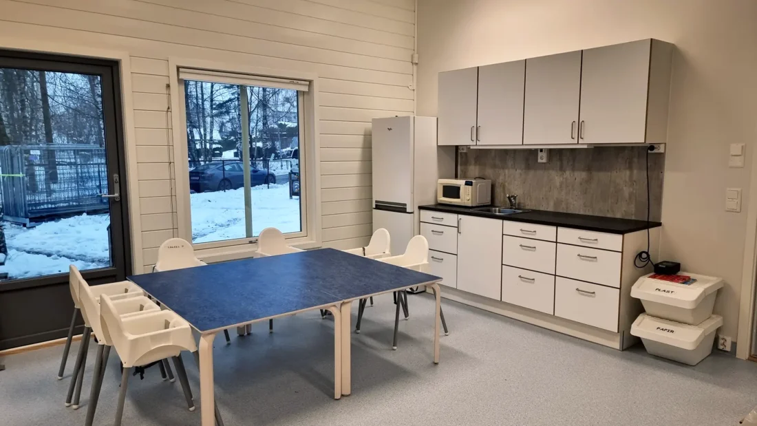 et av kjøkken områdene til Skogveien barnehage etter rehabilitering. her med stort blått bord, med stoler rundt og nytt kjøkken,